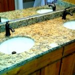 granite bathroom vanity with two sinks and wooden drawers