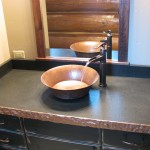 bathroom countertop with hand-chiseled edges and running water from faucet